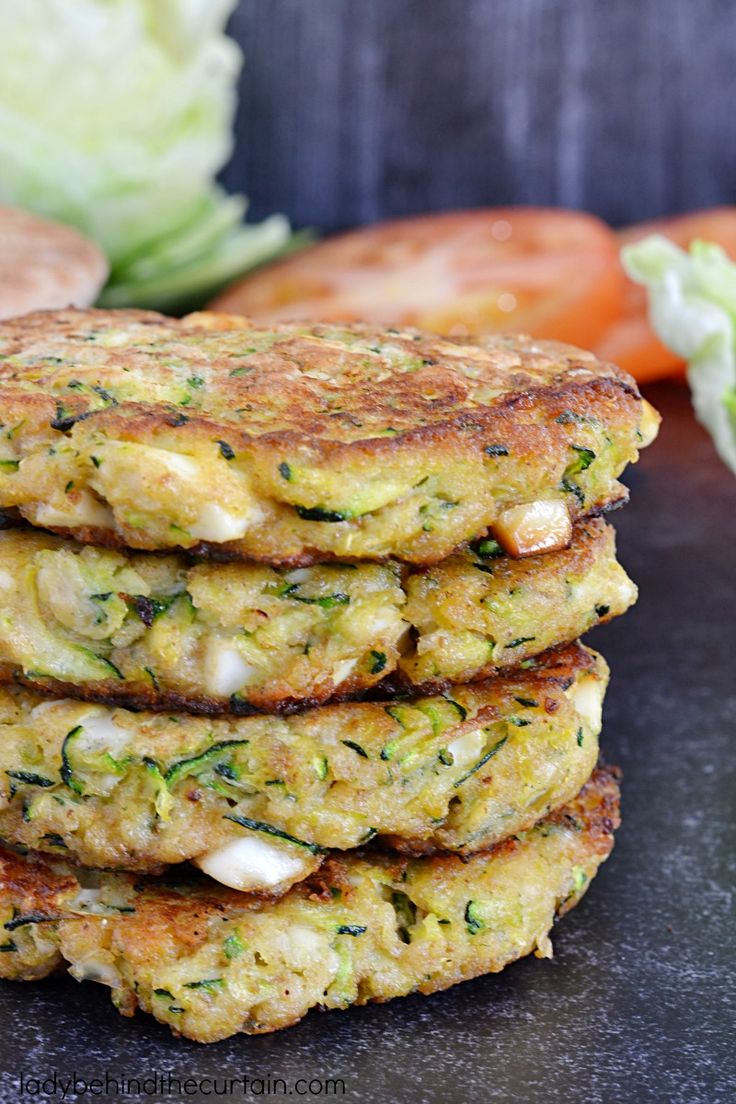 a stack of crab cakes with lettuce and carrots on the side next to it