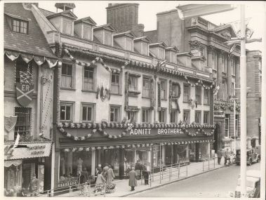 an old black and white photo of people walking down the street in front of buildings