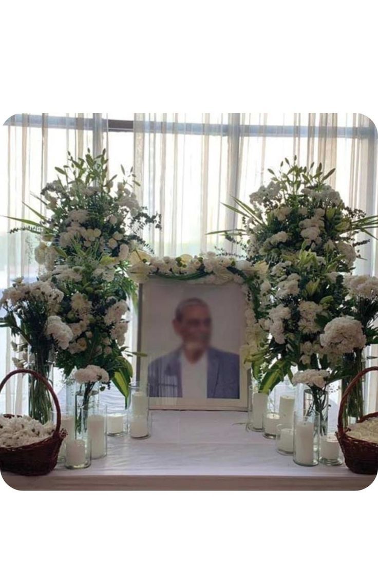 an arrangement of flowers and candles on a table with a photo frame in the middle