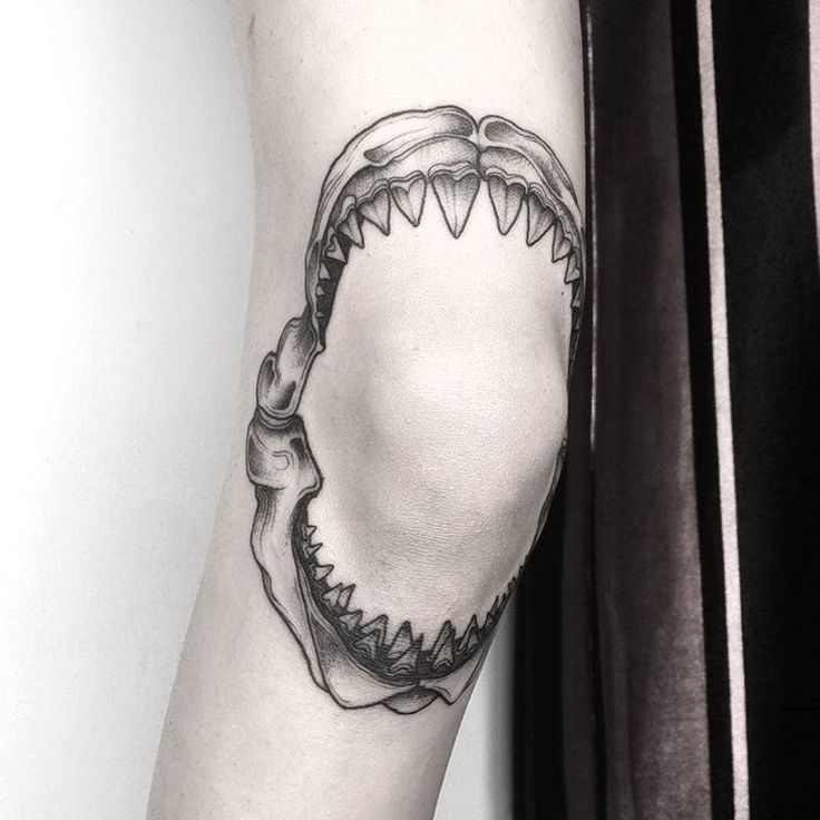 a black and white photo of a shark's teeth tattoo on the right arm