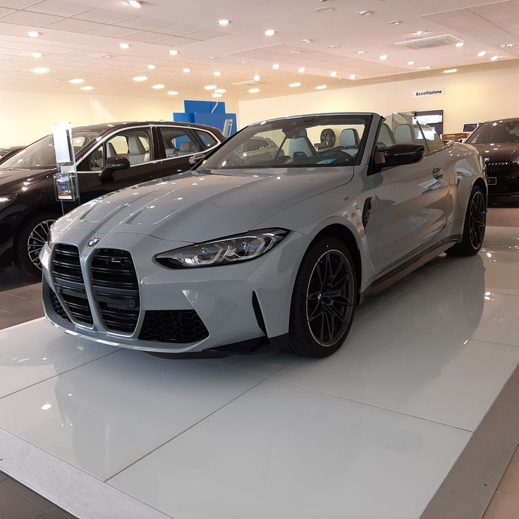 a white sports car is on display in a showroom with other cars behind it