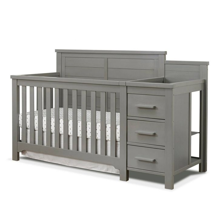 a gray crib with drawers and white sheets