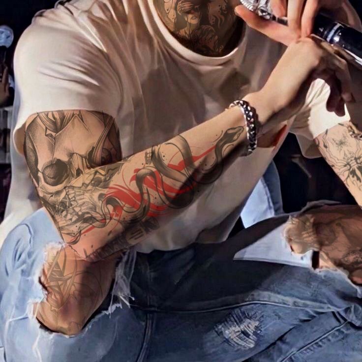 a man with tattoos on his arms and arm holding a cell phone to his ear