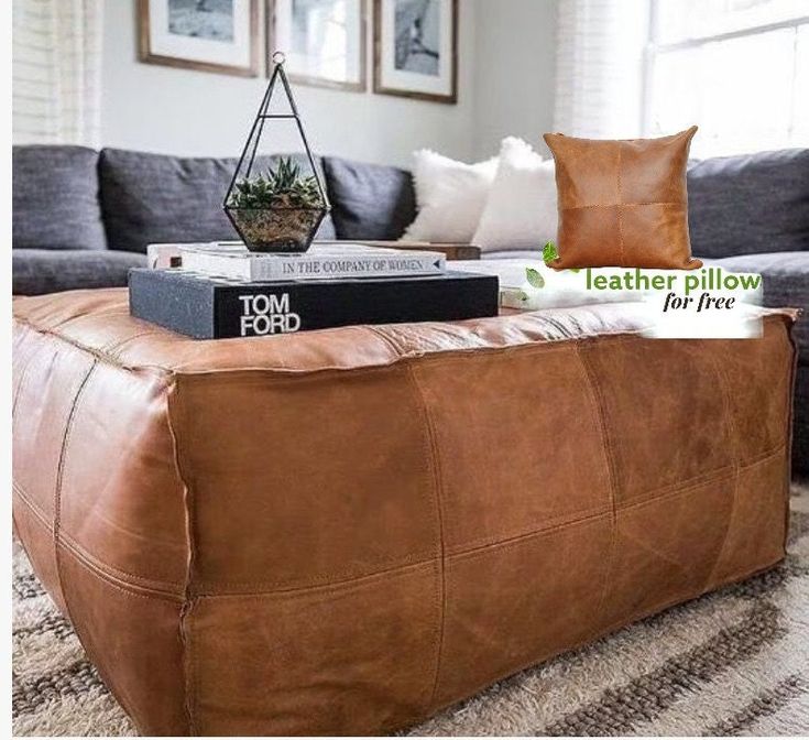 a living room with a couch, ottoman and books on the coffee table in front of it