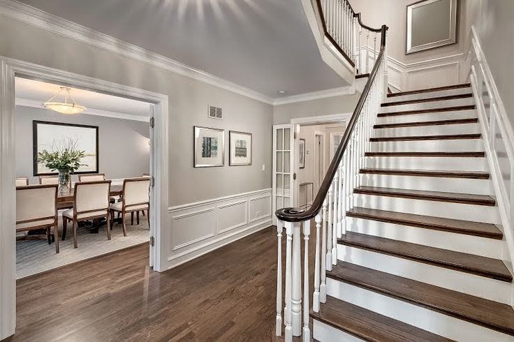 a staircase leading up to a dining room and living room in a house with hardwood floors