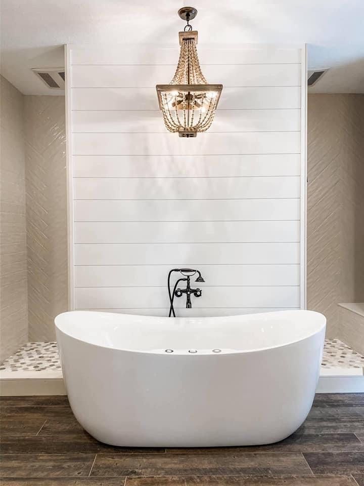 a large white bath tub sitting in a bathroom next to a chandelier hanging from the ceiling