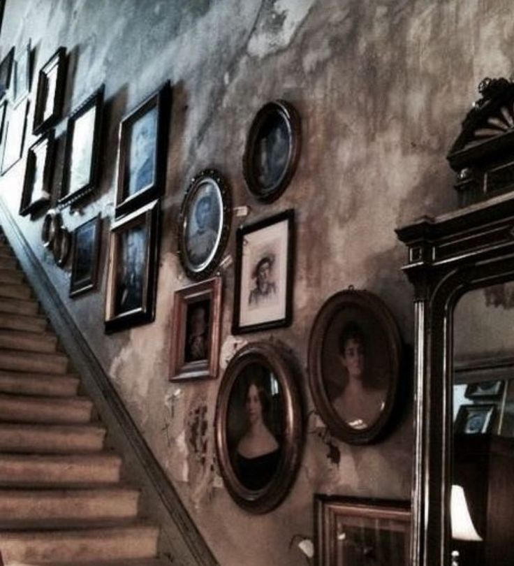 a staircase with pictures on the wall next to it and a mirror in front of it