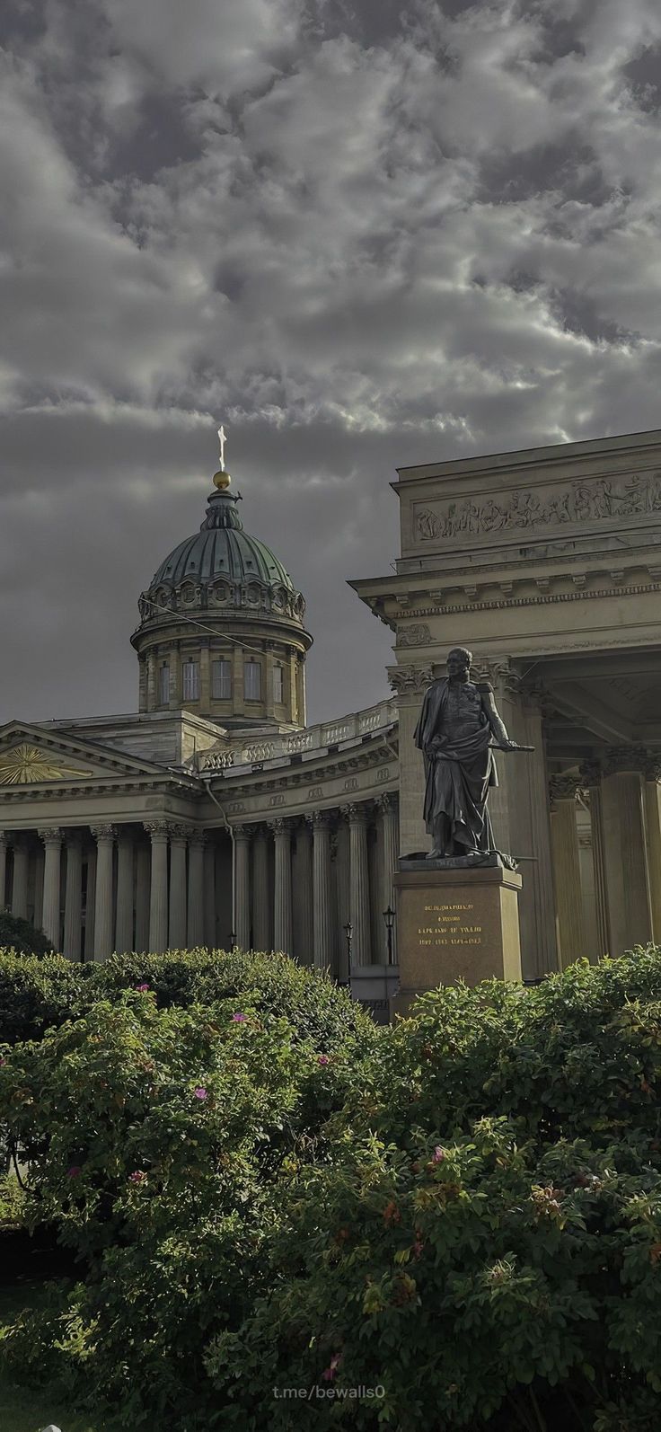 an old building with a statue in the foreground and a cloudy sky above it