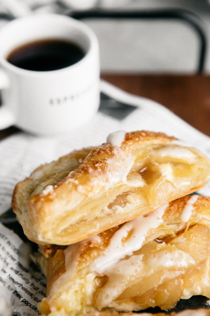 two pastries sitting on top of a napkin next to a cup of coffee