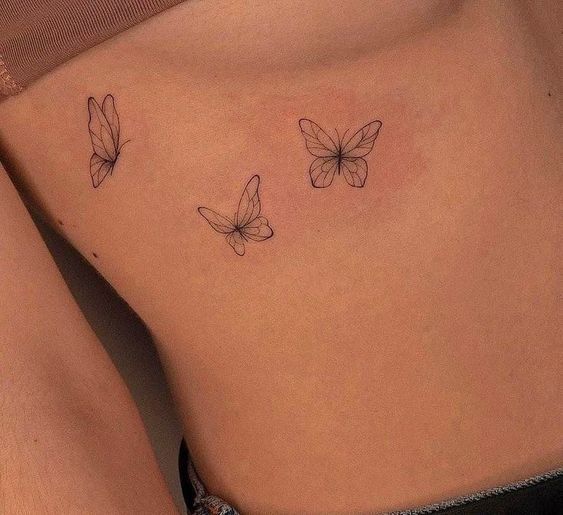 a woman's stomach with three butterflies on the side, and one is black