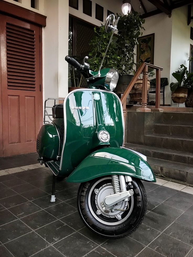 a green scooter parked in front of a house