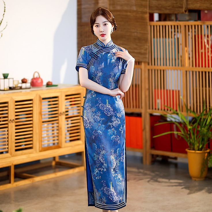 Step into timeless elegance with this stunning blue Qipao / Cheongsam, perfect for any special occasion. This dress features an intricate pattern of peony flowers. The high mandarin collar and short sleeves add a touch of traditional charm, while the white piping and diagonal closure with frog buttons enhance its classic appeal. Ideal for weddings, tea ceremonies, or any event where elegance is key. Size Guide: Size Bust(cm) Waist(cm) Hip(cm) Shoulder(cm) Length(cm) M 86 70 90 37 125 L 90 74 94 Elegant Fitted Blue Cheongsam, Spring Formal Short Sleeve Cheongsam, Blue Fitted Cheongsam With Stand Collar, Fitted Floral Print Cheongsam With Short Sleeves, Elegant Blue Cheongsam For Spring, Fitted Short Sleeve Floral Cheongsam, Traditional Short Sleeve Fitted Cheongsam, Traditional Blue Ao Dai For Formal Occasions, Traditional Short Sleeve Cheongsam For Spring