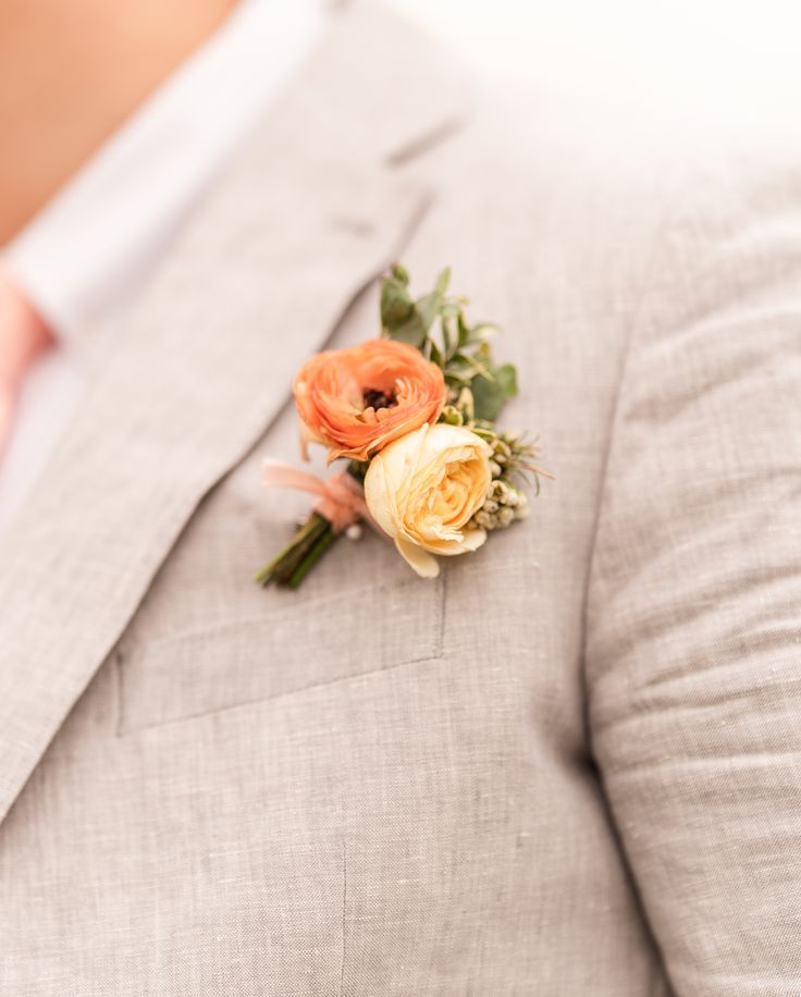 an orange boutonniere on the lapel of a man in a gray suit