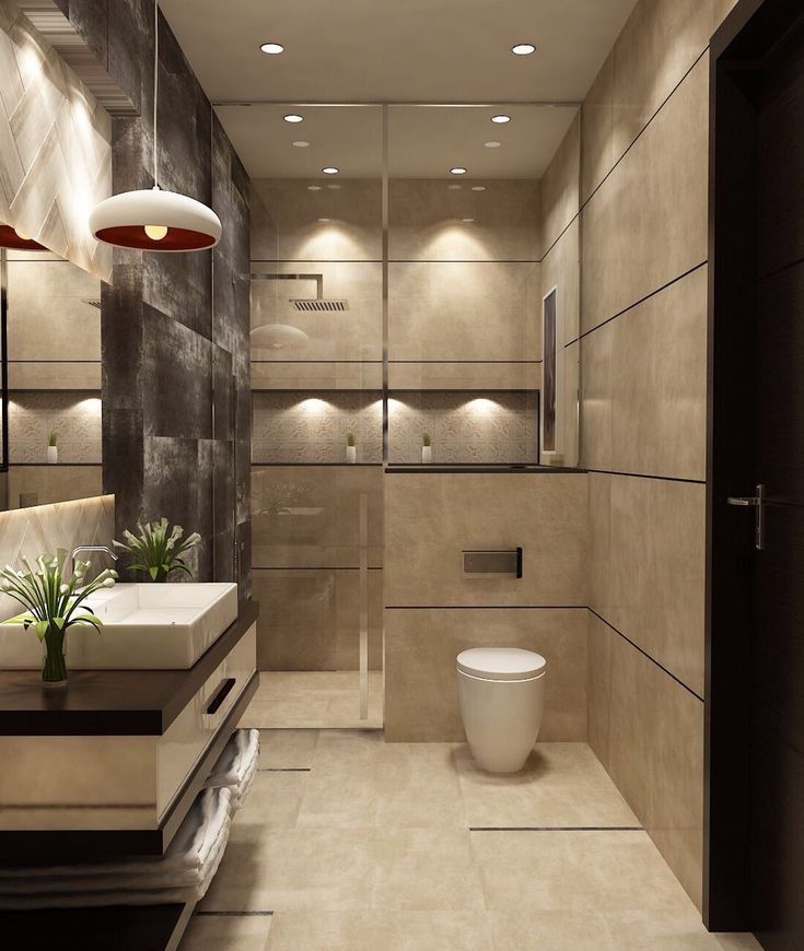 a bathroom with a toilet, sink and mirror in it's center wall is lit by recessed lights