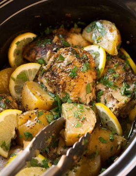 a slow cooker filled with chicken, potatoes and lemons