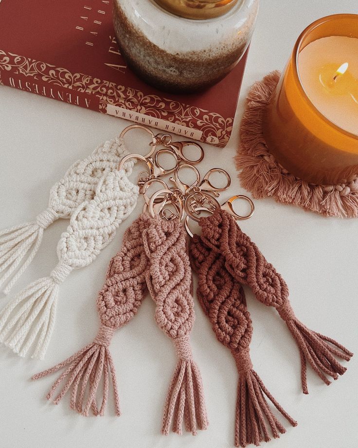 several tasselled key chains sitting next to a candle