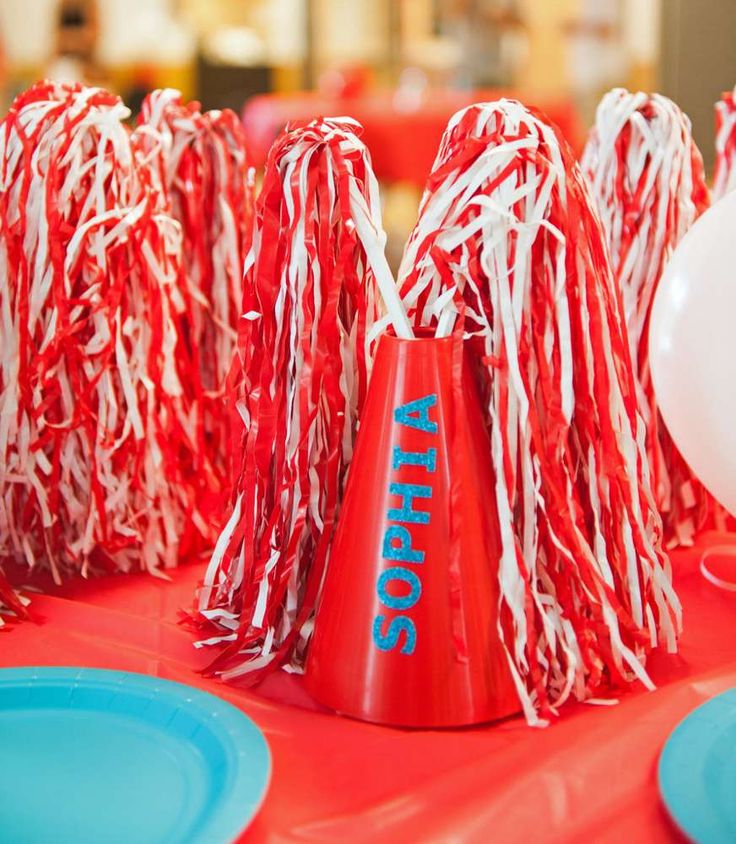 some red and white candy canes are on a table with plates, cups and balloons