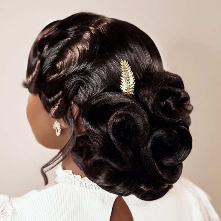 the back of a woman's head with curly hair and a gold leaf brooch