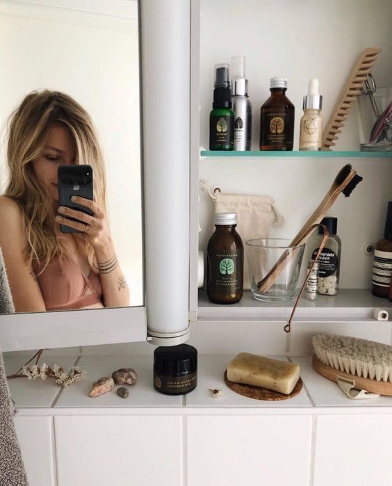 a woman taking a selfie in front of a bathroom mirror while brushing her teeth