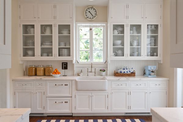 a kitchen with lots of white cabinets and counter top space next to a clock on the wall