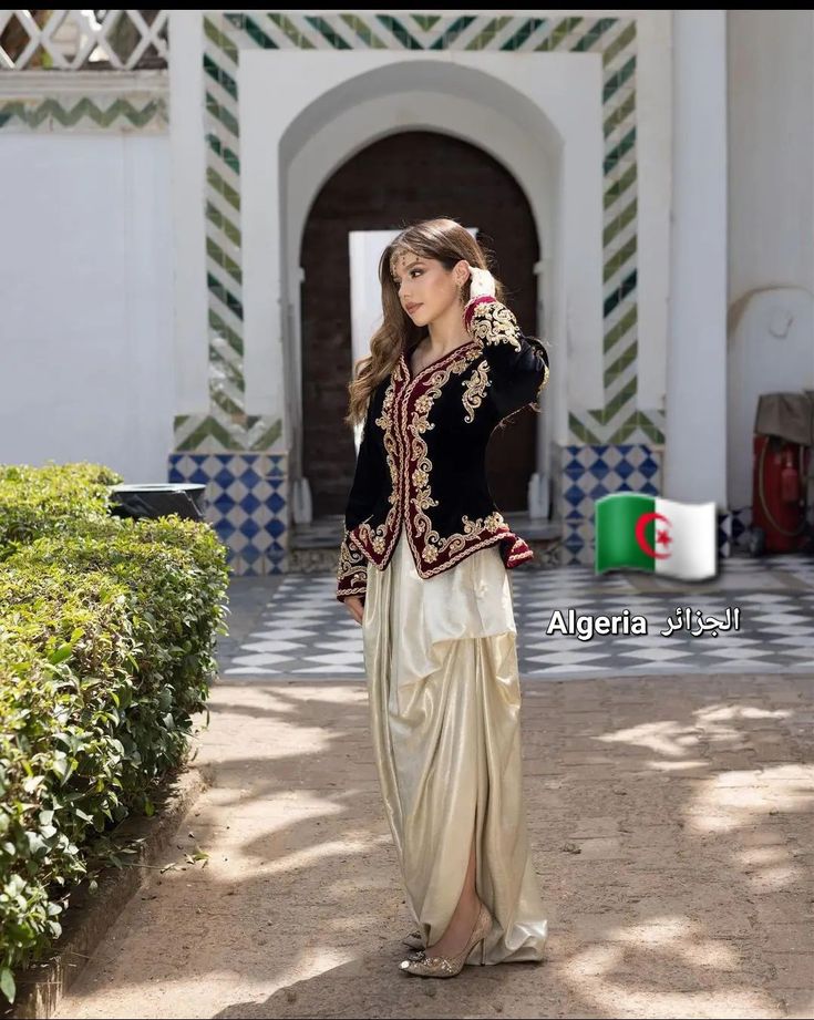 a woman standing in front of a building wearing a black and white outfit with gold accents