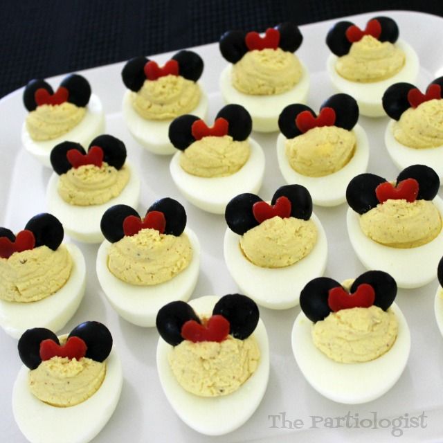 deviled eggs decorated with mickey mouse ears and red heart eyes are arranged on a white surface