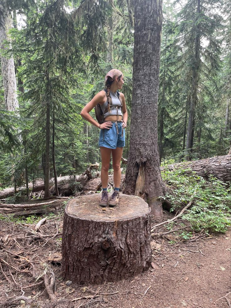 a woman standing on top of a tree stump