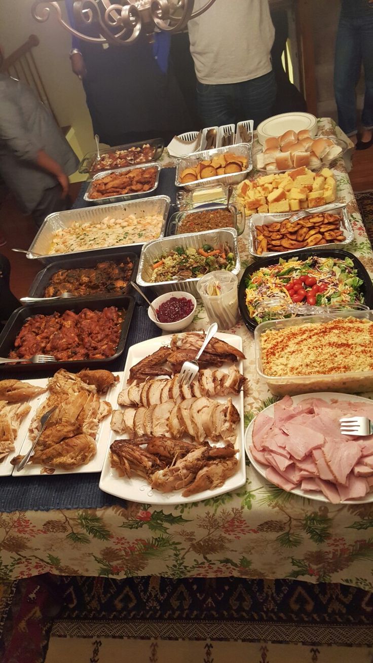 a table filled with lots of food and people standing in the background looking at it