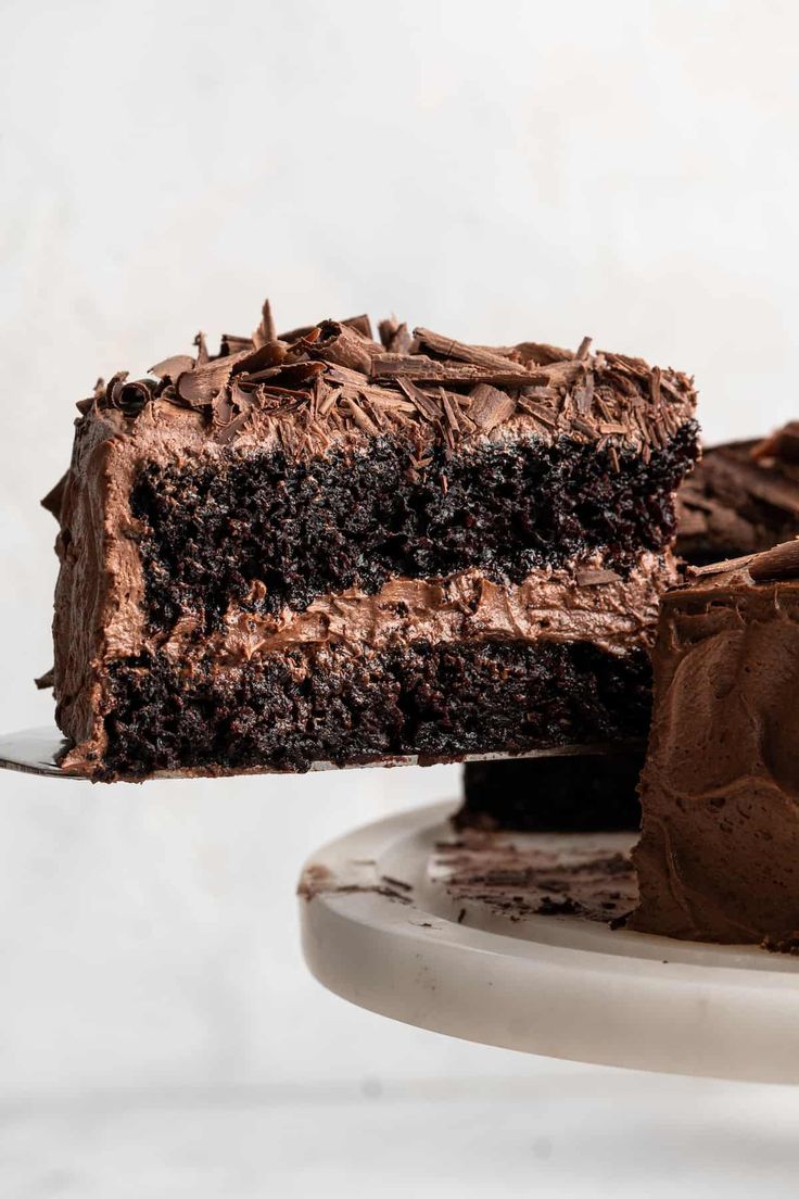 a slice of chocolate cake on a white plate with a piece taken out of it