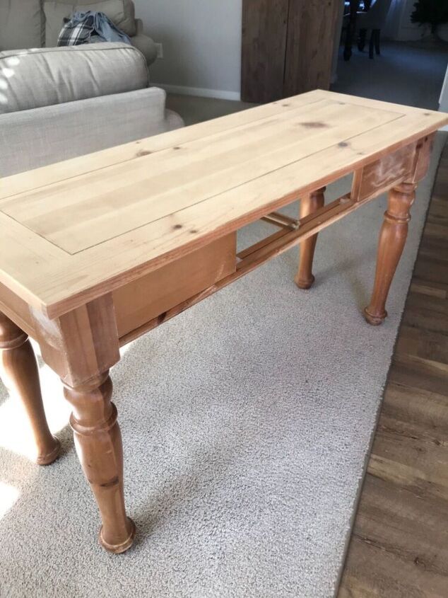 a wooden table sitting on top of a carpeted floor next to a white couch