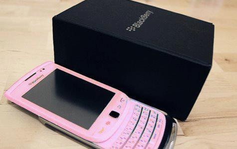 a white cell phone sitting on top of a wooden table next to a black box