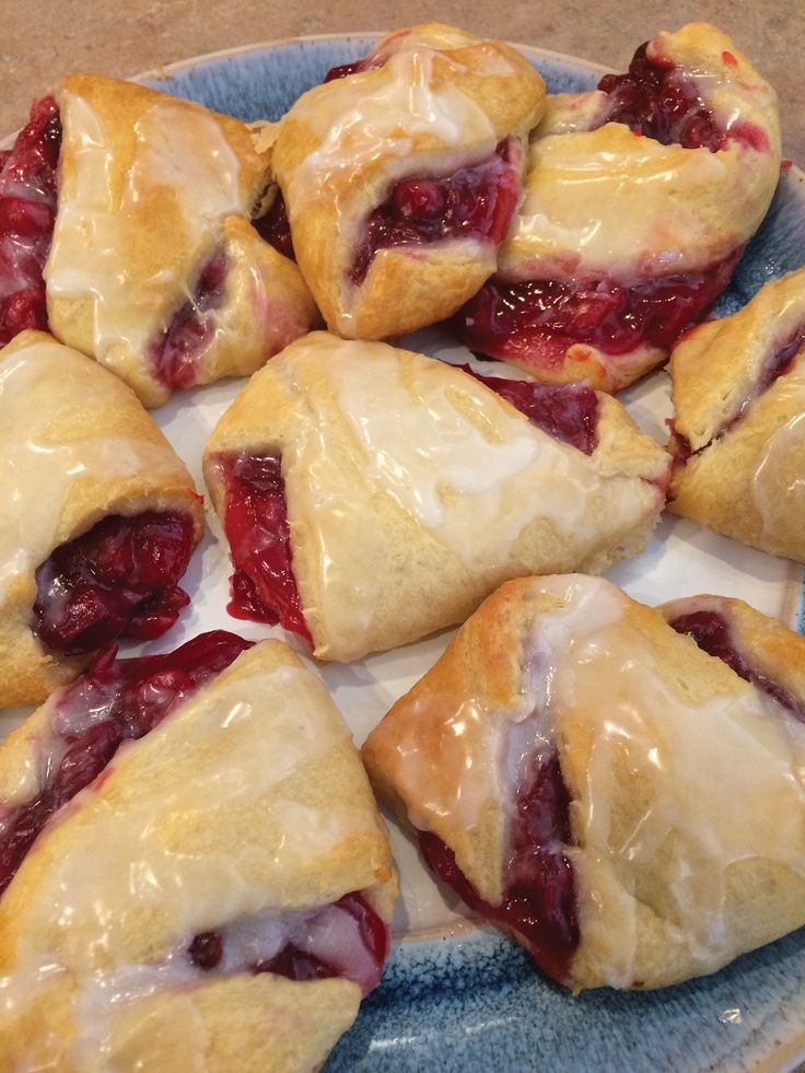 several pastries on a plate covered in icing and cranberry toppings