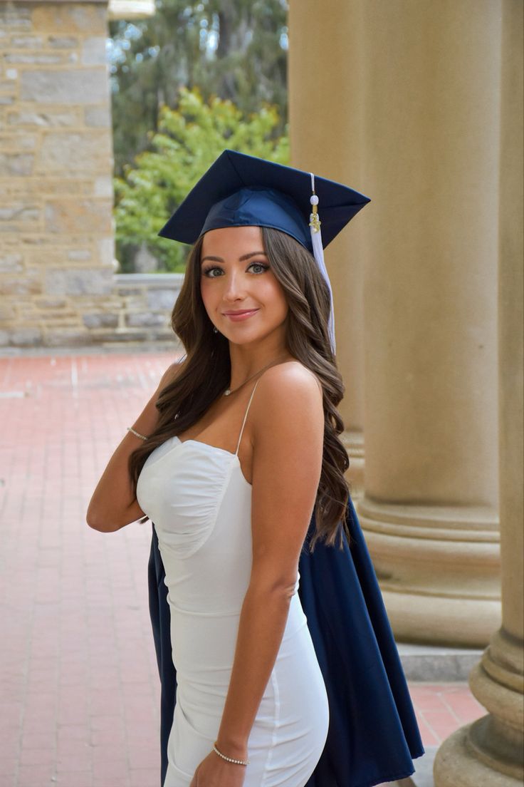 a beautiful young woman wearing a graduation cap and gown posing for a photo in front of columns