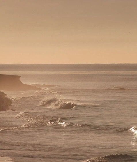 two people walking on the beach with surfboards