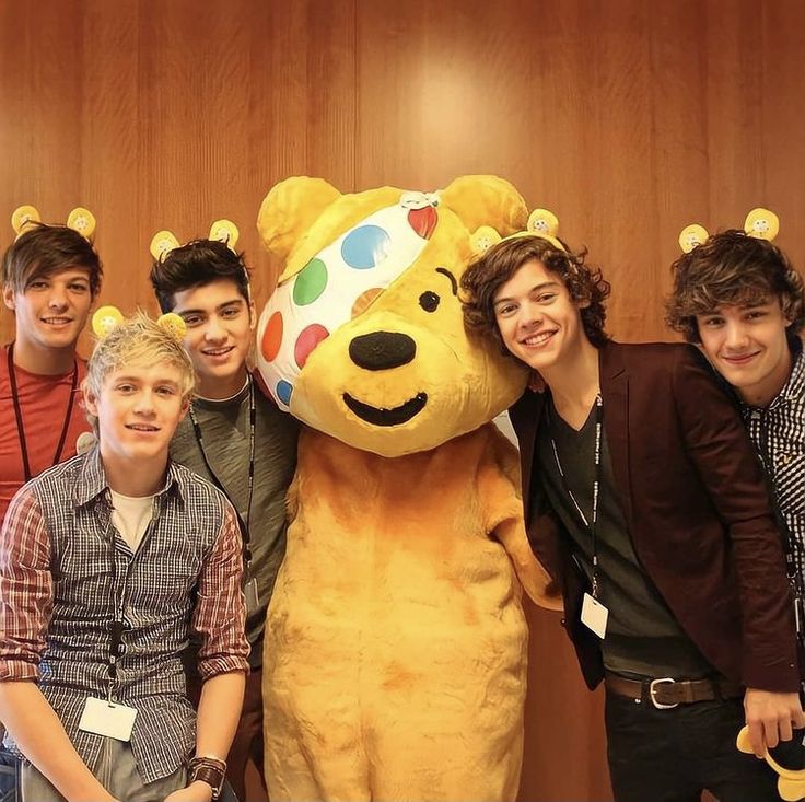 the boys are posing for a photo next to a large teddy bear with balloons on it's head