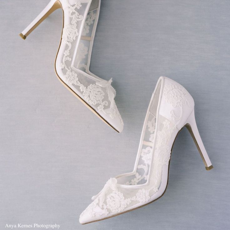 two white high heels with lace on them