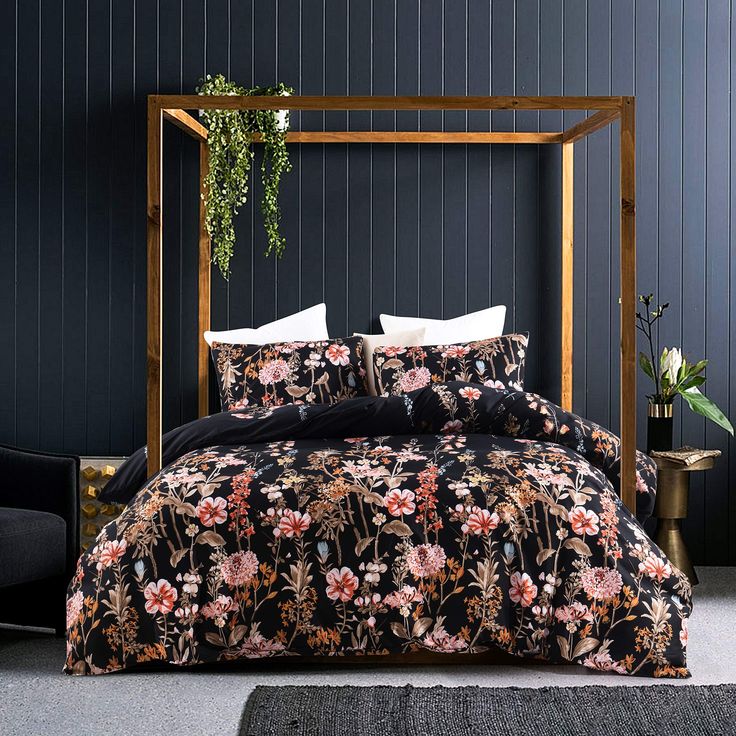 a bed with black and pink floral bedspread in a dark blue walled room