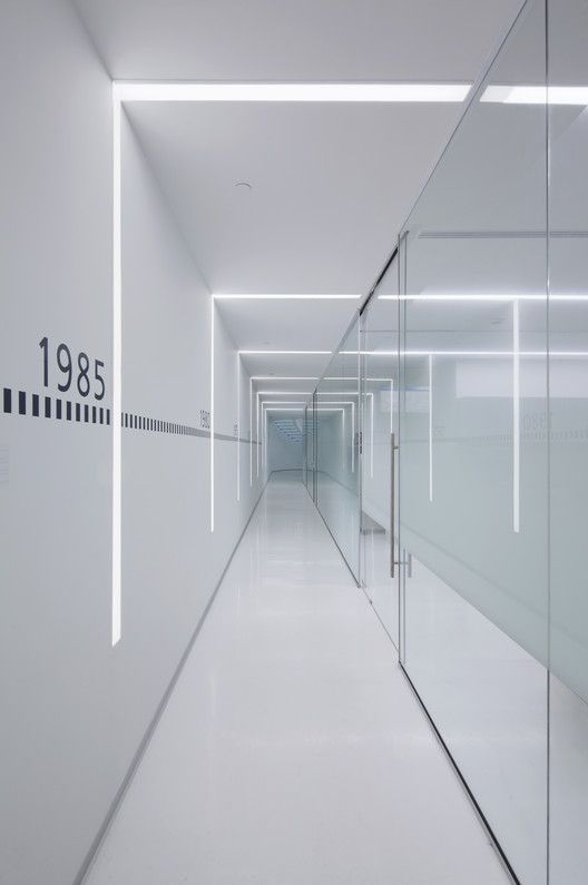 a long white hallway with glass walls and numbers on the wall