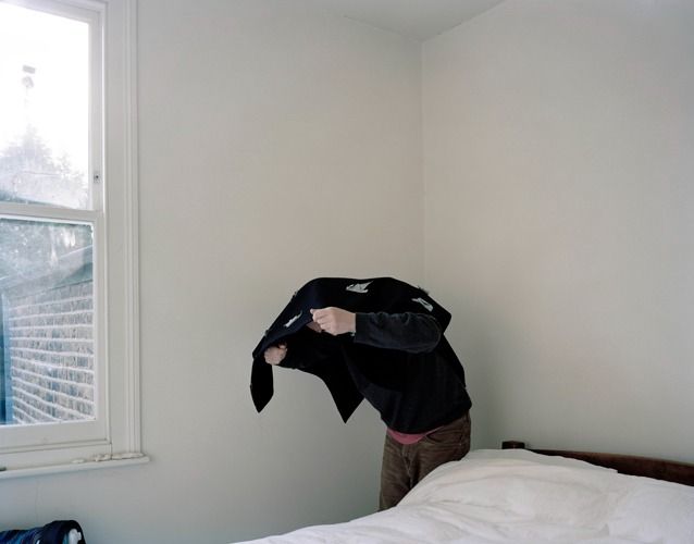 a person standing in front of a bed with a black jacket on top of it