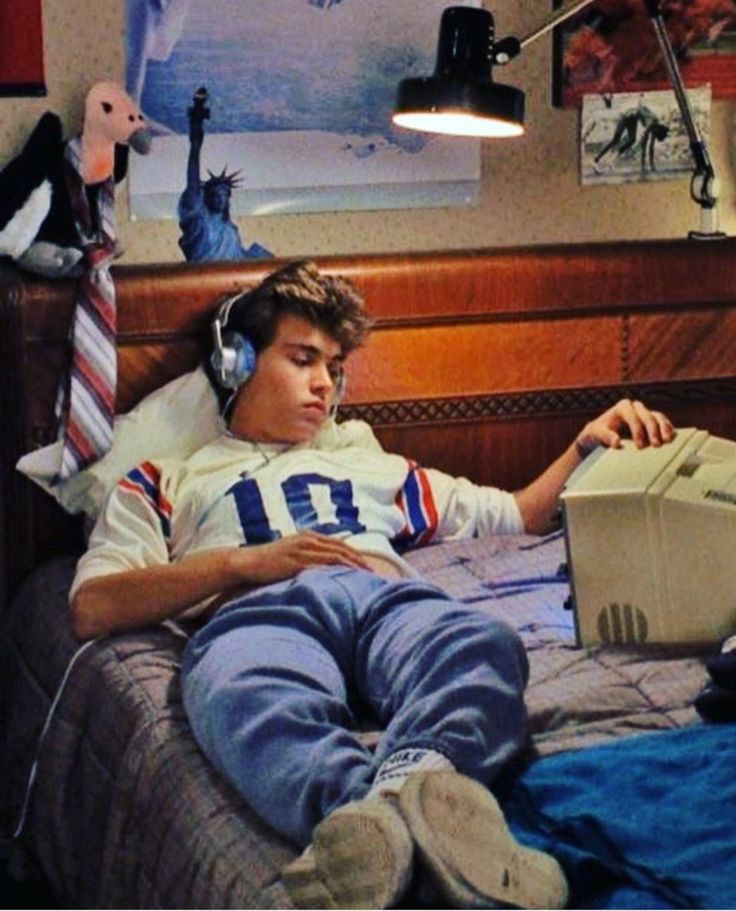 a young man laying in bed with headphones on