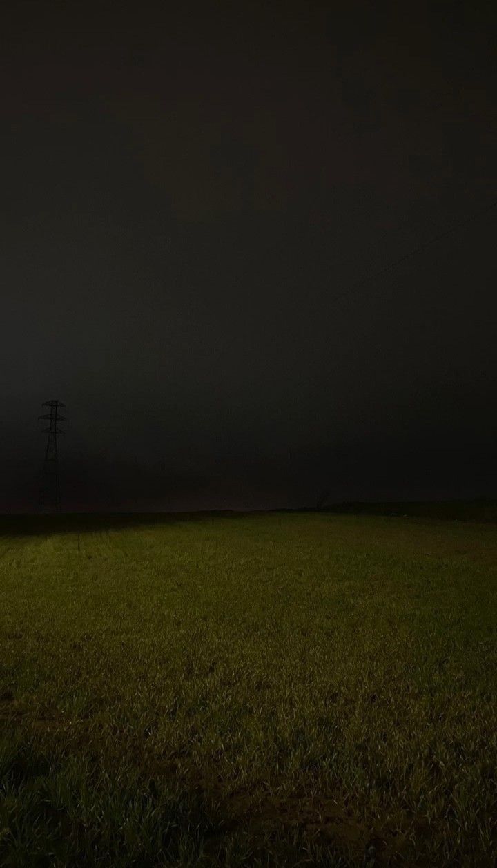 an empty field at night with power lines in the distance