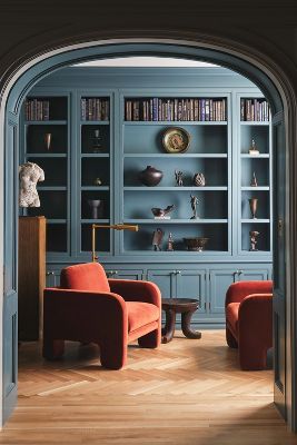 an archway leads into a living room with blue bookcases and orange chairs