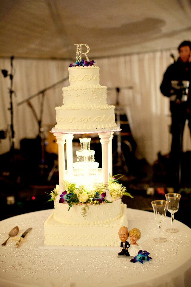 a white wedding cake sitting on top of a table with figurines next to it