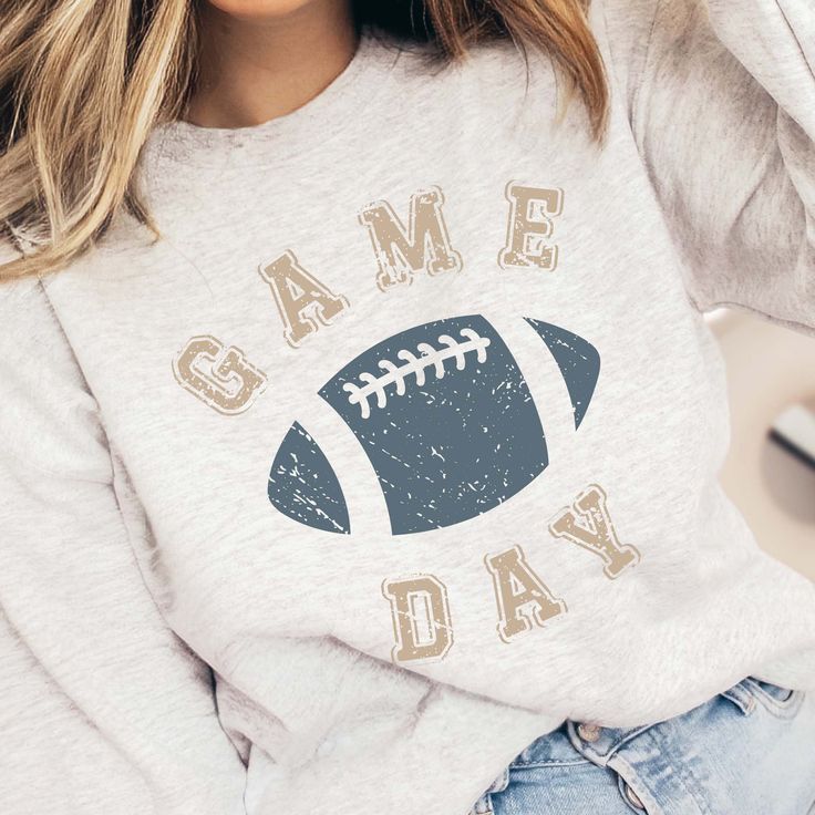 Hey there, football fan! Ready to elevate your game day style with a touch of rugged charm? Our Game Day Blue Football Sweatshirt features distressed text and a football graphic, perfect for showcasing your love for the game with a trendy edge. Whether you're at the stadium, hosting a tailgate party, or cheering from home, this sweatshirt combines comfort with a bold design. Crafted from ultra-soft, high-quality fabric, our Game Day Blue Football Sweatshirt ensures warmth and durability throughout the season. Its relaxed fit and premium material keep you cozy and stylish as you cheer for your team from kickoff to the final whistle. The distressed text and football graphic add a unique and rugged element to your game day wardrobe. This sweatshirt pairs effortlessly with jeans, leggings, or Game Day Team Spirit Sweatshirt With Lettering, Team-colored T-shirt For Game Day In Fall, Team Spirit Game Day T-shirt For Fall, Team Spirit T-shirt For Game Day In Fall, Football Season Graphic Print Sweatshirt, Sports Fan T-shirt For Game Day In Fall, Football Season Team Spirit Tops With Lettering, Team Name T-shirt For Fall Game Day, Varsity T-shirt With Lettering For Game Day