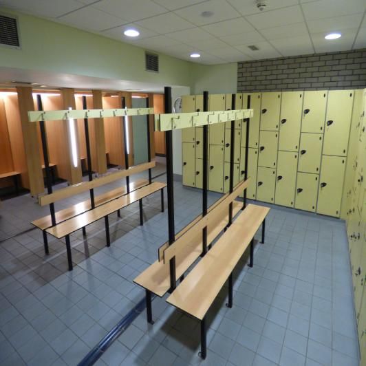 an empty locker room with several benches in front of the lockers and lights on the wall