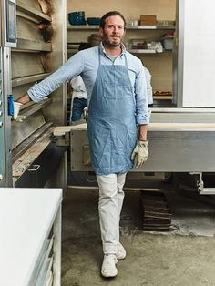 a man in an apron standing next to a food truck with shelves full of items