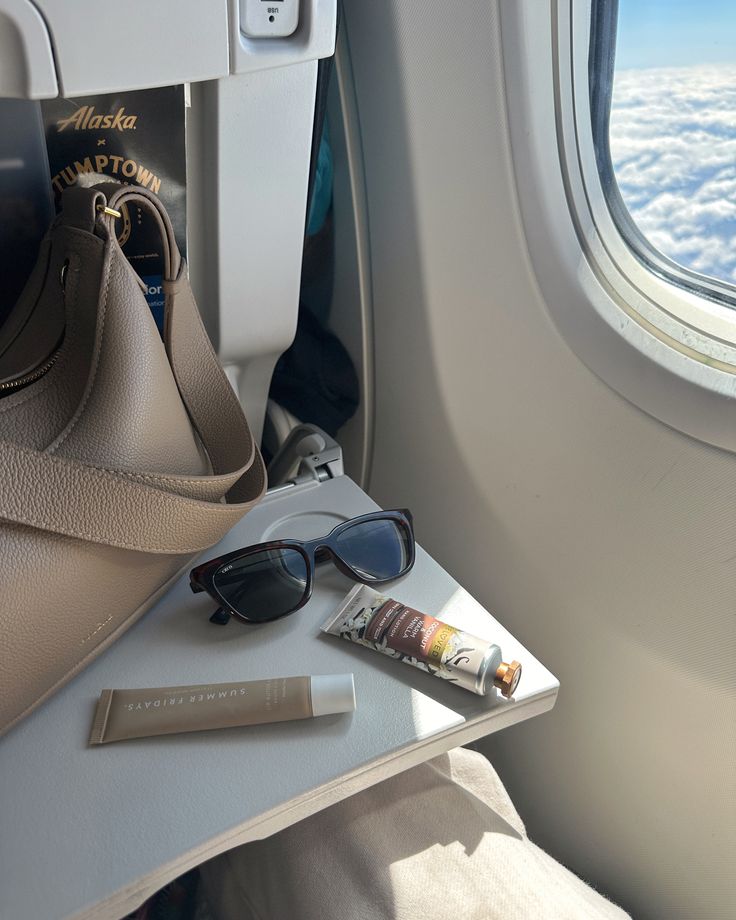 an airplane seat with sunglasses and a book on it