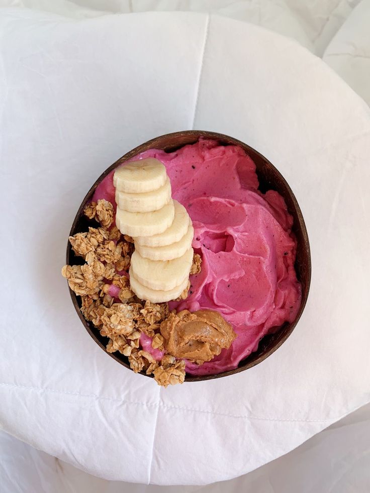 a bowl filled with fruit and granola on top of a white tablecloth covered table