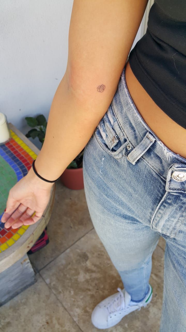 a woman with a small tattoo on her left arm standing next to a skateboard