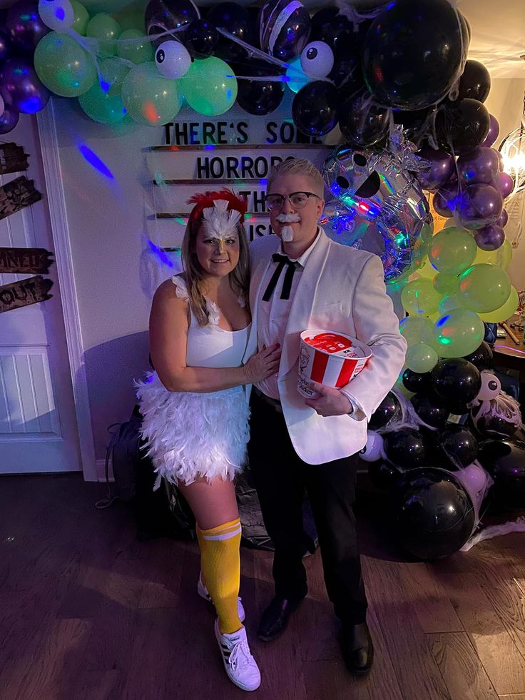 a man and woman dressed up in costumes posing for a photo with balloons behind them